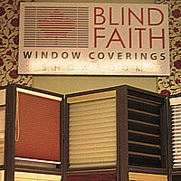 A sign saying Blind Faith Window Coverings above a display of blinds
