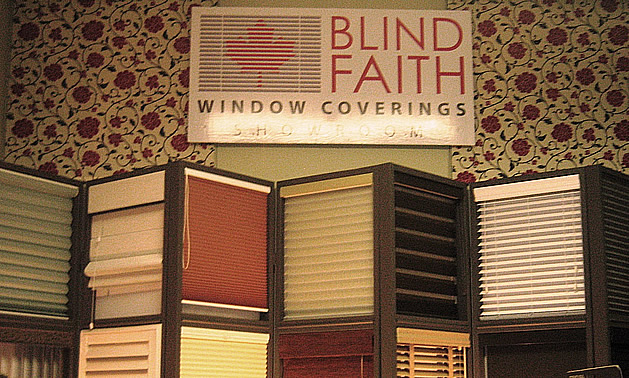 A sign saying Blind Faith Window Coverings above a display of blinds