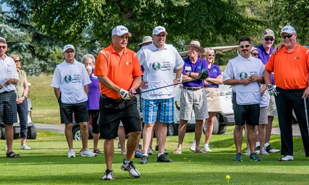 A blind golf competitor uses the assistance of a coach as he sets up a shot.
