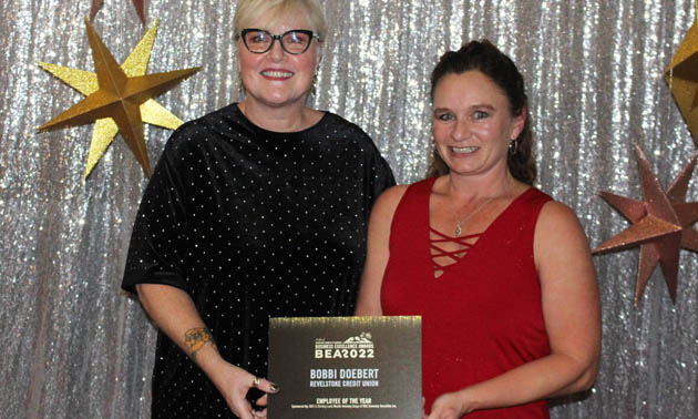 Bobbi Doebert, holding her Employee of the Year award and smiling into camera. 