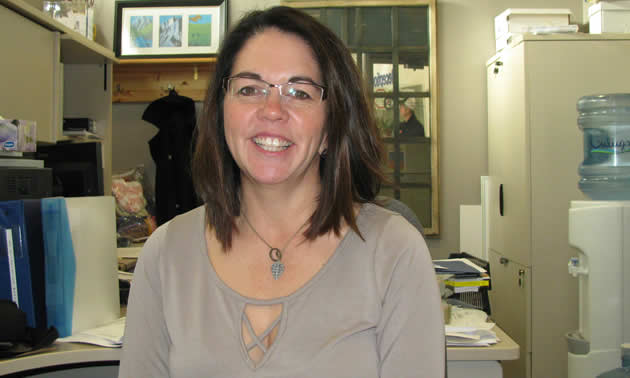 Brenna Baker, executive director of the East Kootenay Foundation for Health, stands before the Foundation logo and the donor recognition board at the East Kootenay Regional Hospital.