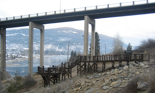 Concrete pillars support a streamlined pedestrian walkway high above a river