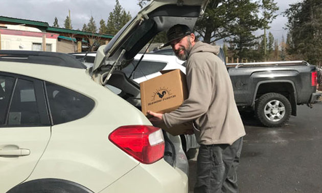 Butcher Trevor Shulist loading a box into car. 