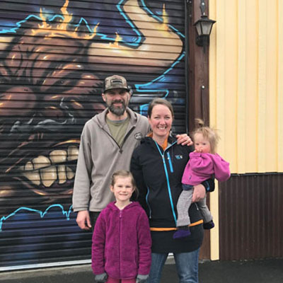 Trevor and Jessica Shulist and family standing in front of their business. 