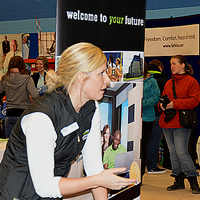 A woman representing Lethbridge College interacts with two attendees at the College of the Rockies Career and Job Fair.