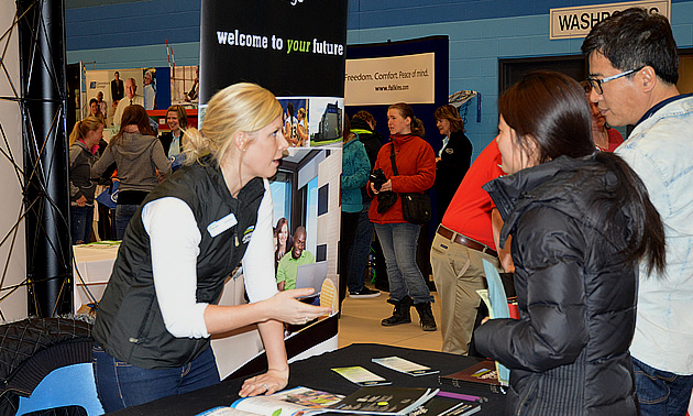 A woman representing Lethbridge College interacts with two attendees at the College of the Rockies Career and Job Fair.