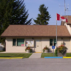 Small house attached to two-bay firehall, with Canada flag flying out front