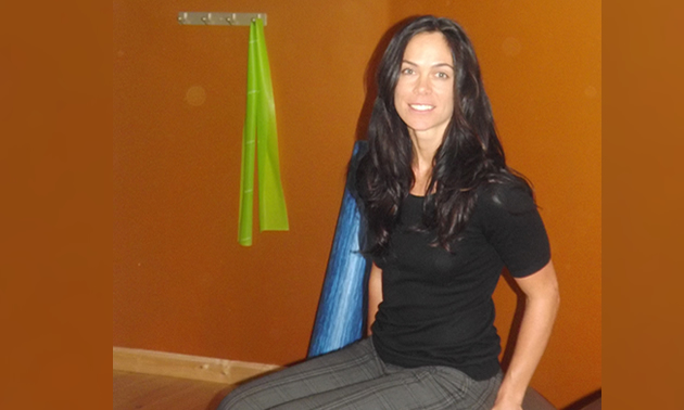 a youthful woman with long dark hair against a rust-brown wall