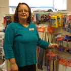 Heather, wearing a blue shirt, stands next to a display of medical aids.