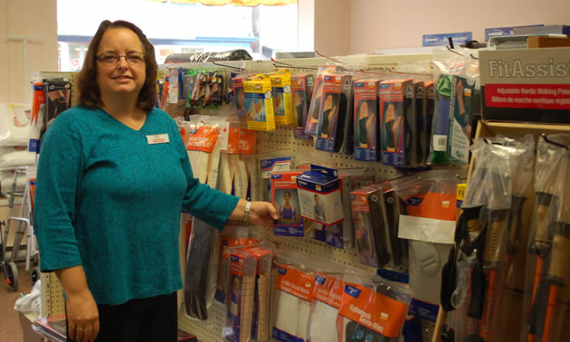 Heather, wearing a blue shirt, stands next to a display of medical aids.