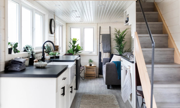 Interior of tiny home, showing white cabinetry and bright interior. 