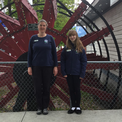 Cedra Eichenauer and Melissa Johnson of the Nakusp and District Chamber of Commerce stand beside the decorative paddlwheel outside the chamber office