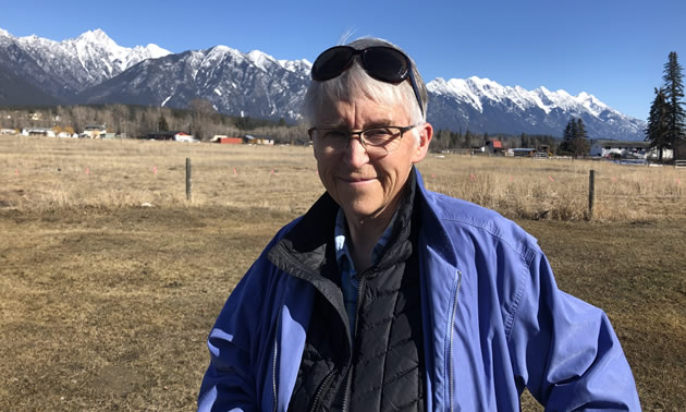 Jan Skiber, posing in front of distant mountains. 