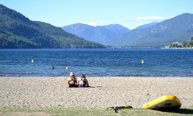 Two children sitting on sunny beachfront. 