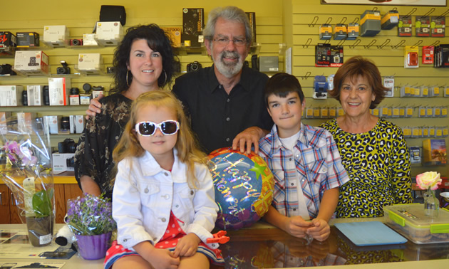 Three adults and two children in front of a merchandise display wall