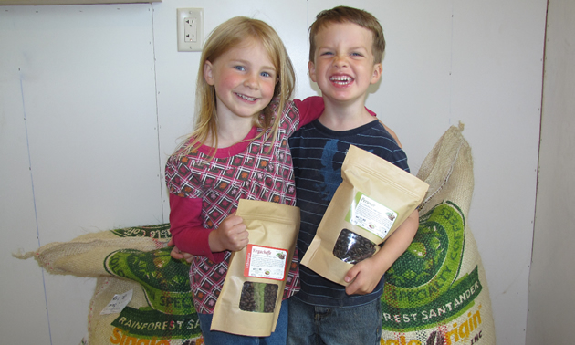 Young girl and boy stand holding identical brown bag packages