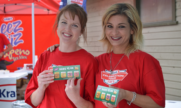 Two smiling young women in red t-shirts displaying Kraft Peanut Butter coupons