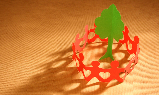 A circle of red paper chain men around a green paper tree.