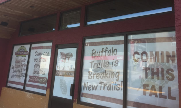 Outside of Buffalo Trails Coffee House, showing signs in window that they are moving. 