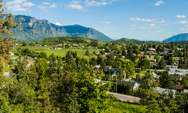 A lush green valley is spread out between blue mountains and sky.