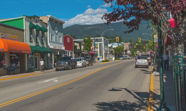 View of downtown Creston street scene showing row of buildings, sidewalk and cars on street. 