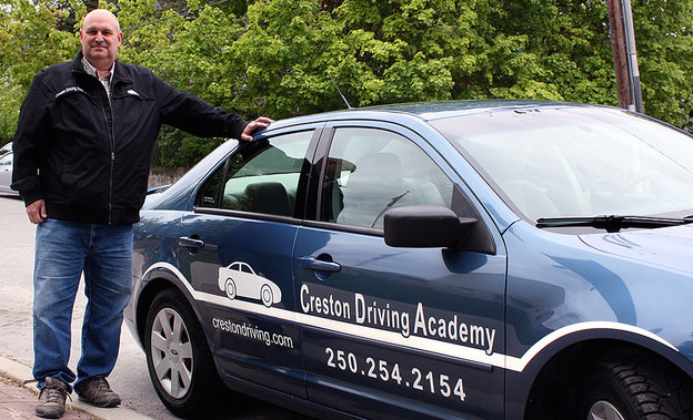 Bill Doeleman, owner and instructor at Creston Driving Academy, is standing next to one of the academy cars.