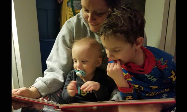 A mother is reading a book to her young son.