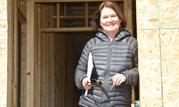 Smiling woman stands in the doorway of a building under construction