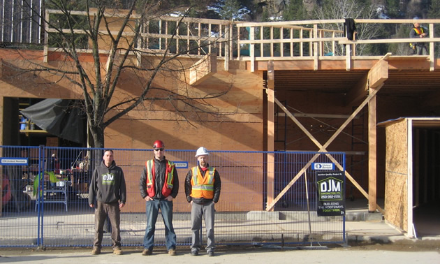 Three workmen stand outside a construction zone