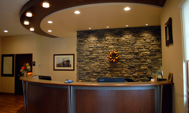 A curved wooden desk has a rock-work wall behind it.