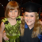Woman in cap and gown standing by a child