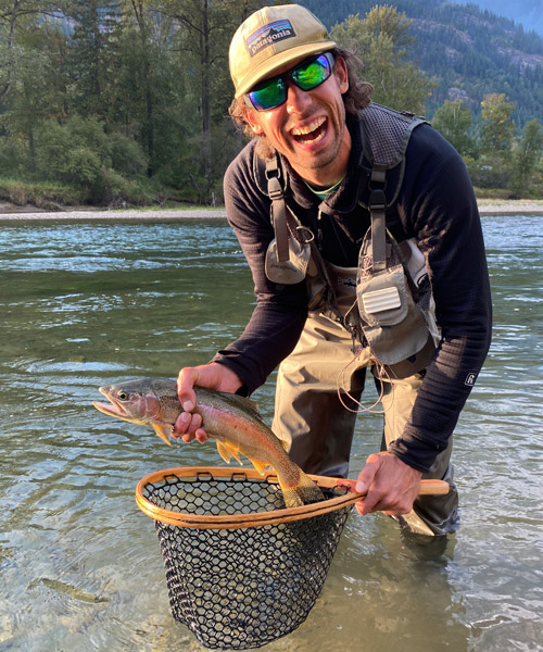 Cam Shute holding fish in river. 