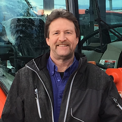 Darrell Kemle, owner of Kemlee Equipment Ltd. in Creston, posed with a large, red Kubota-brand machine.