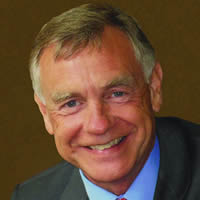 A headshot of David Walls. He wears a suit and smiles for the camera.