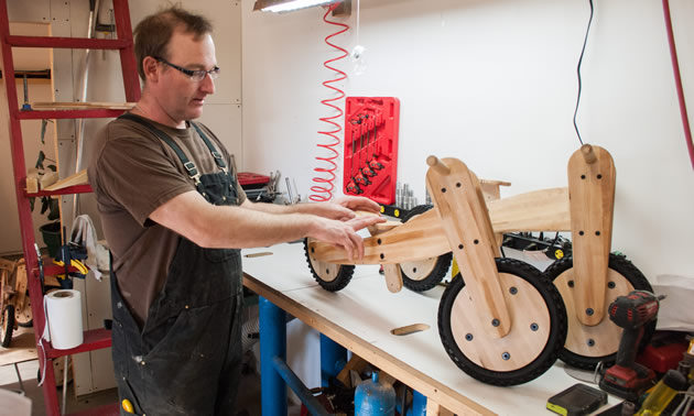 Sheldon DeCosse displays the Maple Rider balance bikes he builds on a workshop table.