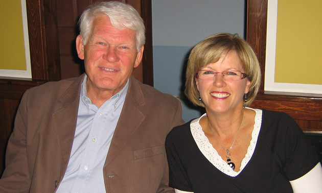 White-haired man and blonde woman smile warmly at the camera