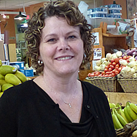 Smiling woman among supermarket displays of bright produce