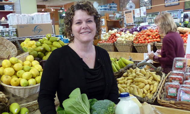Smiling woman among supermarket displays of bright produce