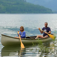 Man and young woman paddling a canoe on a mountain lake