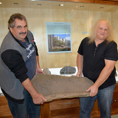 Guy Santucci, Cranbrook History Centre Board Chair, and Jason Jacob, President of East Kootenay Chamber of Mines, with one of the dino prints.