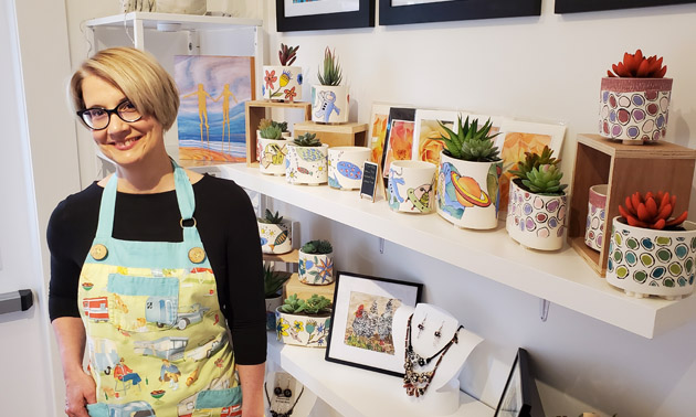 Michele Dupas standing in front of shelf full of arts and paintings. 