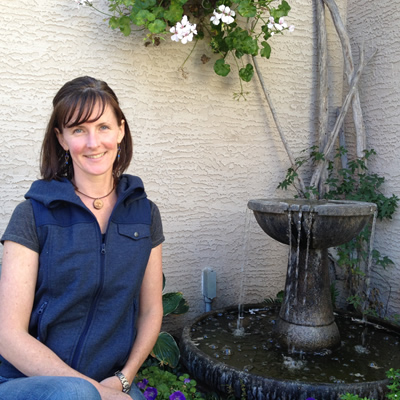 Tammy Bessant sits near a water fountain in front of her house in Cranbrook from which she runs her business, EarthWear.