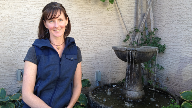 Tammy Bessant sits near a water fountain in front of her house in Cranbrook from which she runs her business, EarthWear.