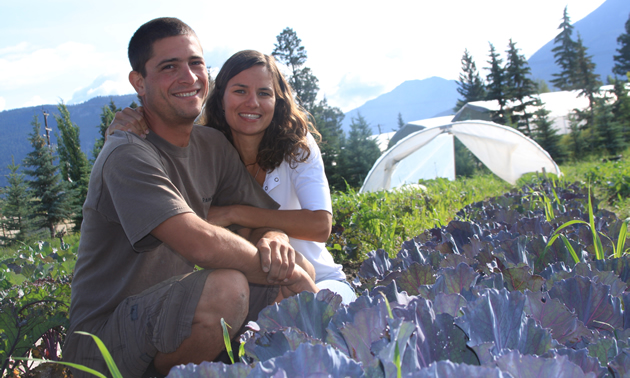 Smiling young couple sitting in a vegetable garden