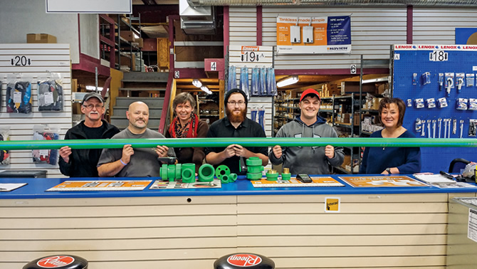 Workers at Emco in Cranbrook are lined up and holding a green pipe made by Aquatherm.