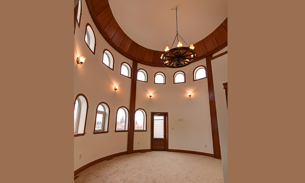 A tall, round room inside the turret has several layers of windows, wood trim and a chandelier.