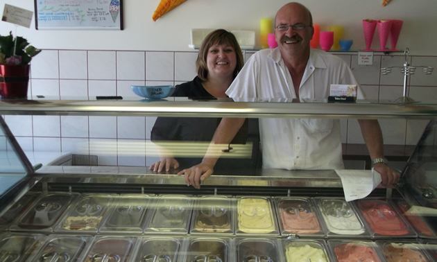 Smiling couple behind a glass cabinet displaying ice cream
