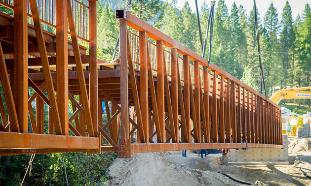 New-looking wooden pedestrian bridge supported by yellow strapping