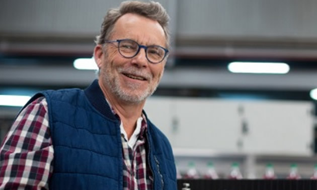 Man wearing a puffy vest and checkered shirt using a tablet. 