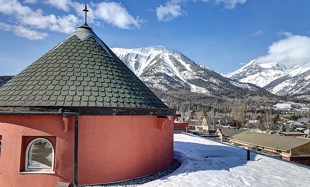 The top of a turret is visible against a background of snowcapped mountains.